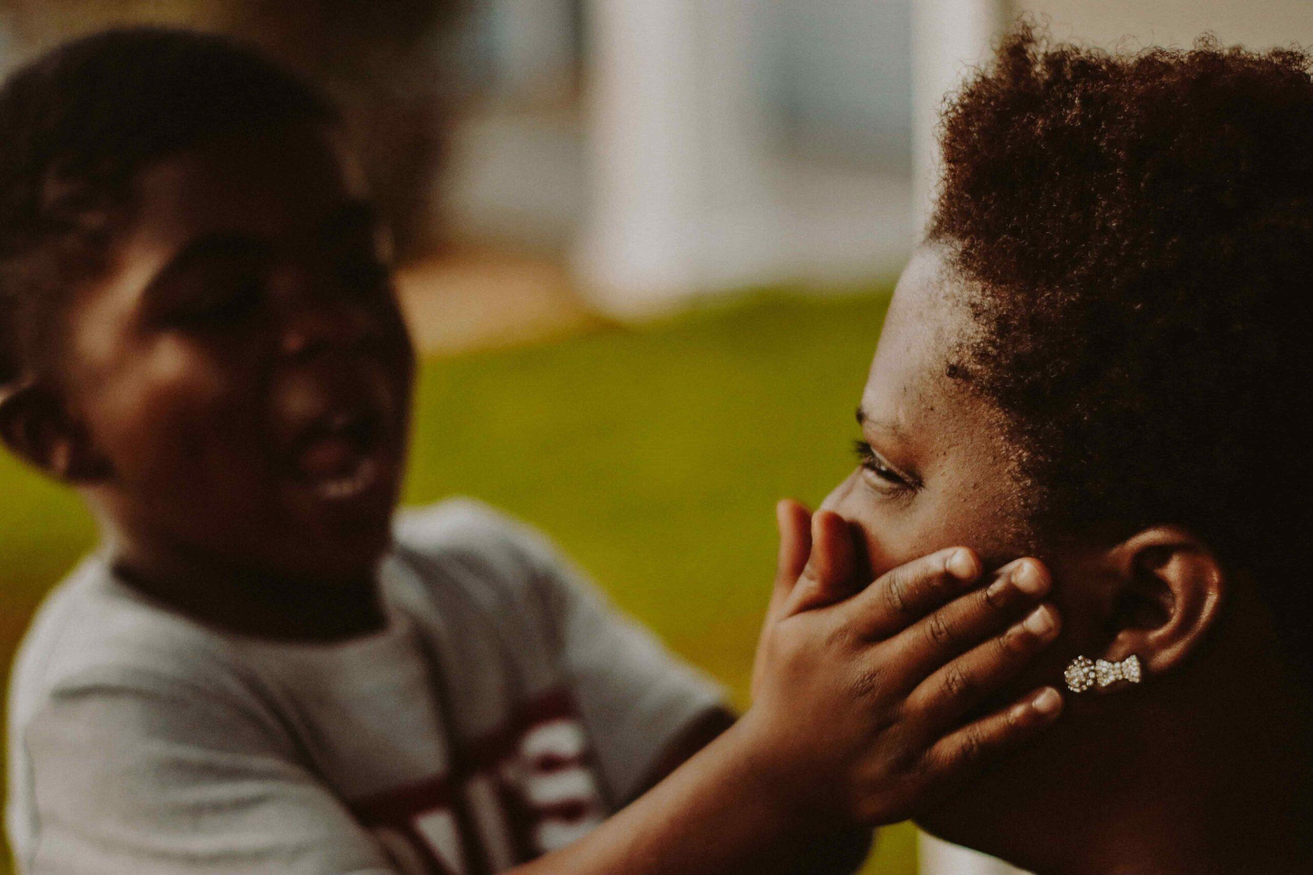 A young child affectionately touches their mother's face, a tender moment of connection and love between parent and child.