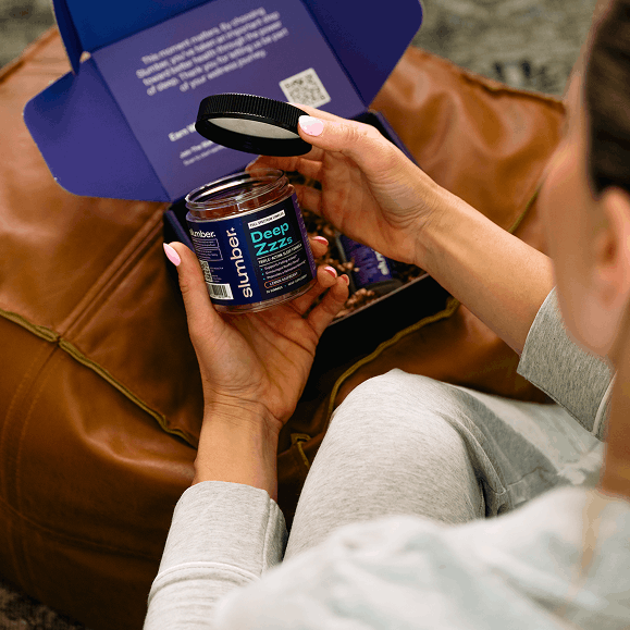 Person holding a Deep Zzz jar product with a purple box in the background