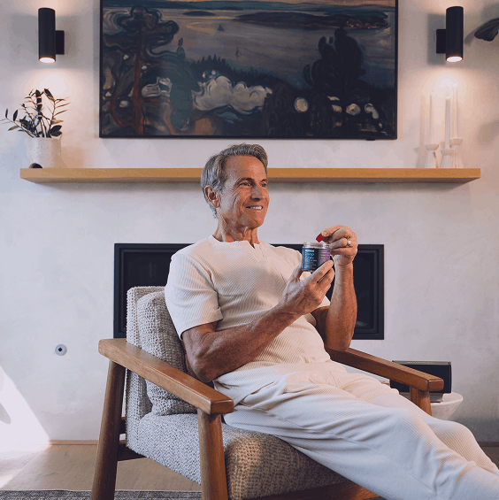 Man sitting in a chair holding a can in a cozy living room.